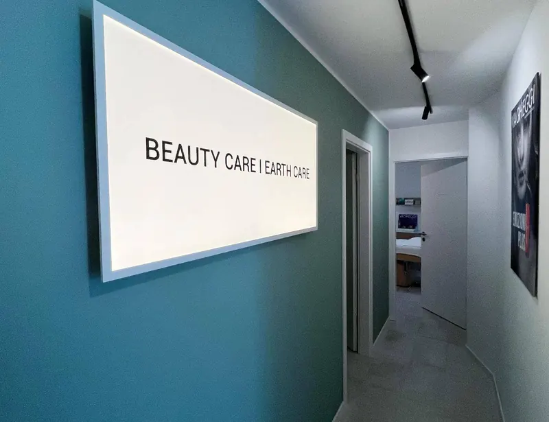 Le couloir de l’institut : mur vert sarcelle et panneau lumineux « Beauty care | Earth care »